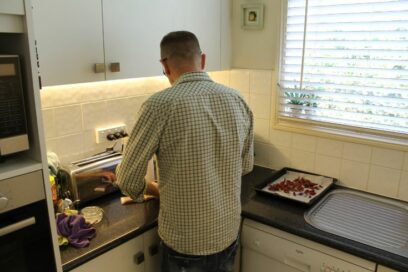 Man standing in a white kitchen with his back turned to the camera